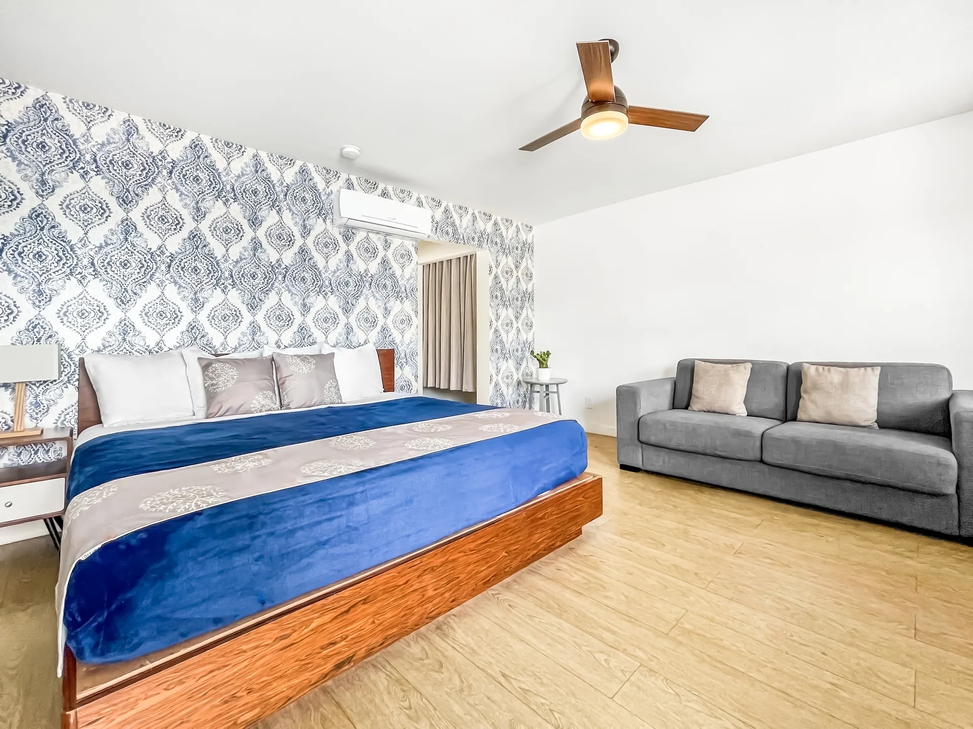 A wide view of a hotel room with a large bed, sofa, and ceiling fan.