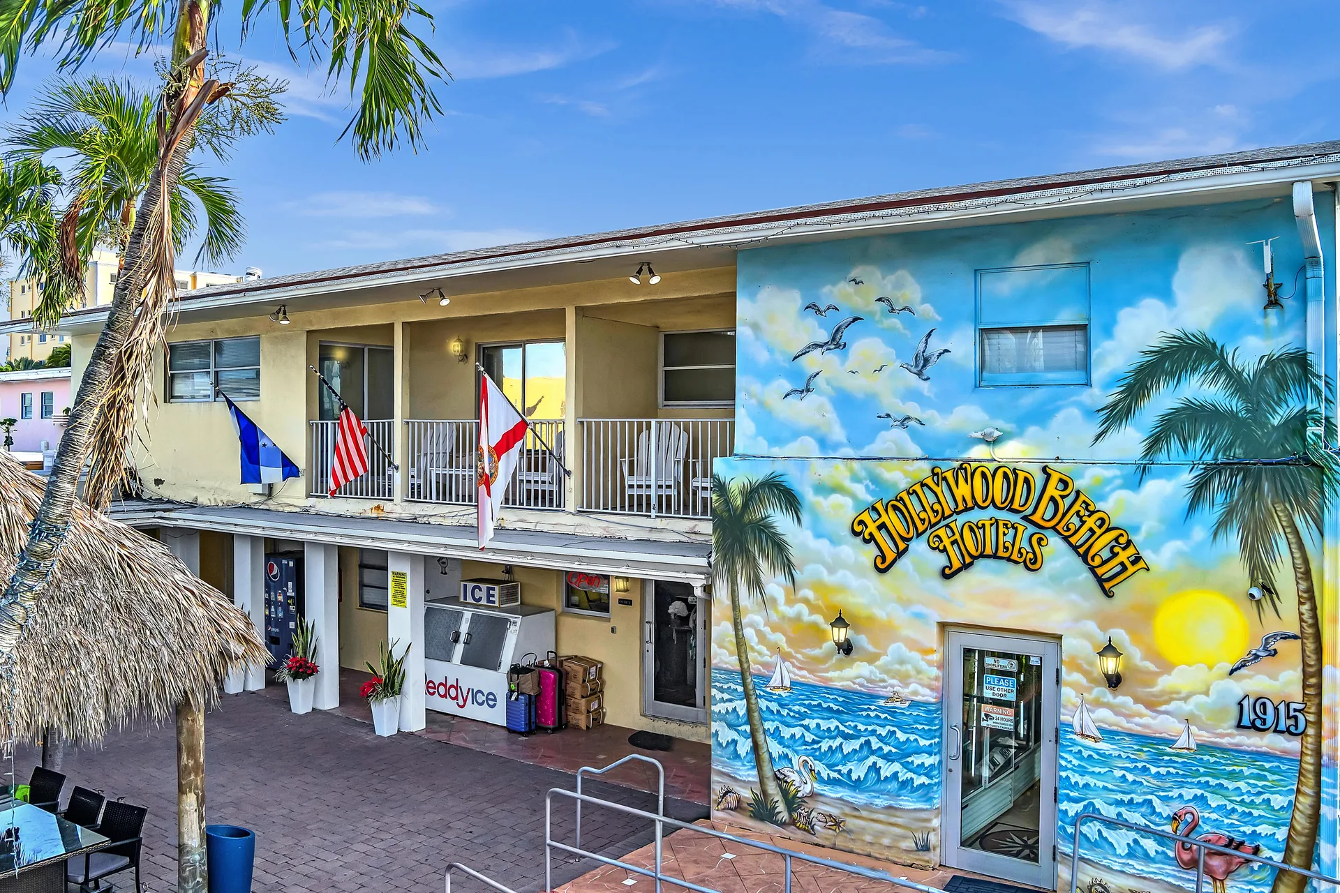 A two-story building with a balcony and a mural on the side.