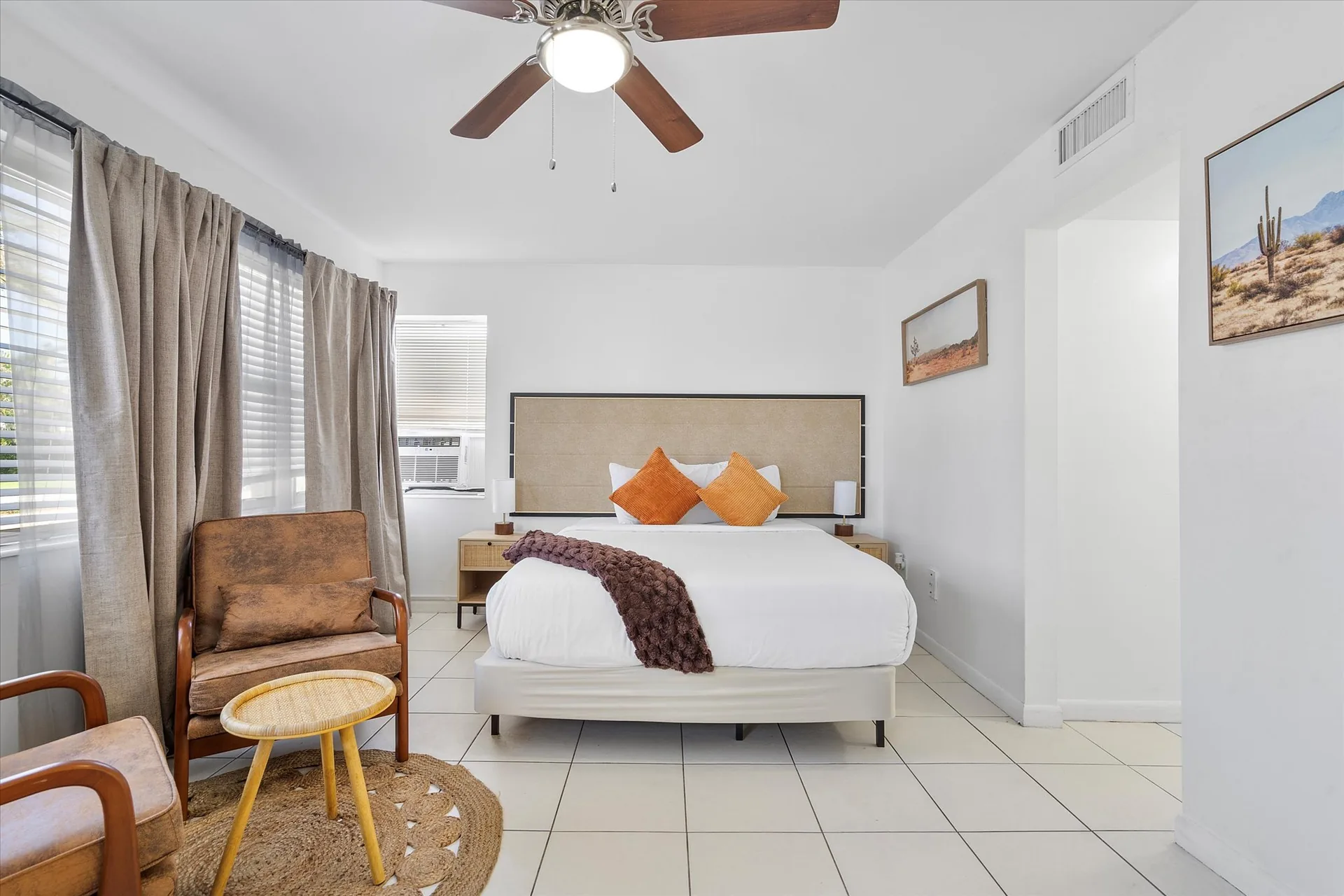 A hotel room with a large bed, chair, and window