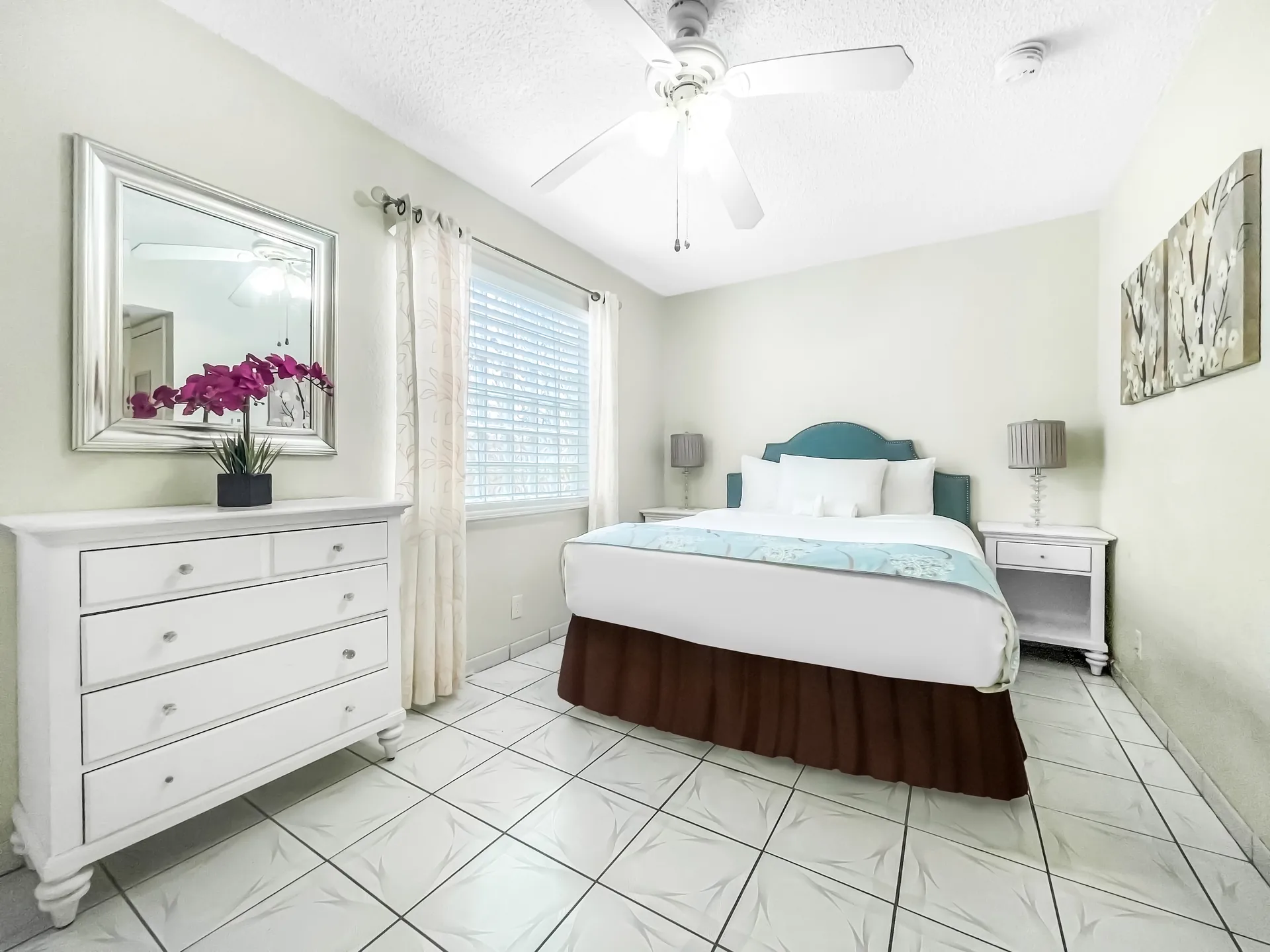 A clean and tidy hotel room with a bed, dresser, and nightstand.
