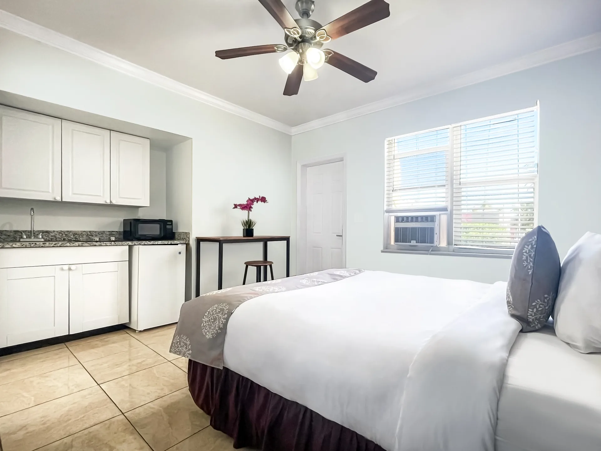 A studio room with a double bed, kitchenette, and window