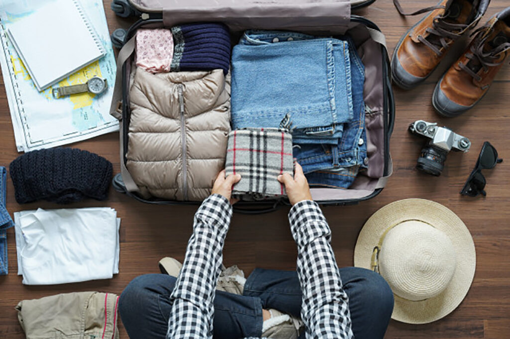 Packing guide - A person sitting on the floor packing things for its desired destination 